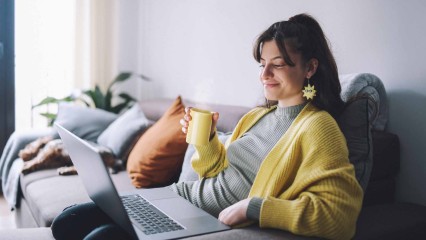 femme souriante qui boit son café devant son ordinateur