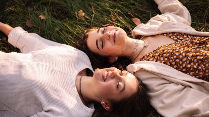 Deux filles allongées dans l'herbe, avec le sourire. 