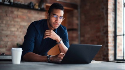 Homme devant son PC, à table