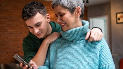Une femme et son fils en train de regarder leur smartphone avec le sourire