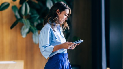 Femme vêtue de bleu, tenant un smartphone dans ses mains
