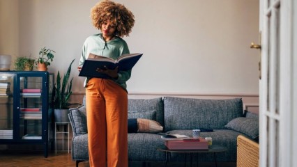 Femme debout parcourant un gros livre
