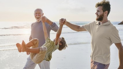 Deux hommes sur la plage soulevant un enfant par les bras
