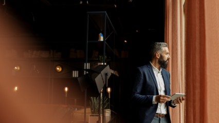 Homme en costume regardant par la fenêtre dans une ambiance feutrée