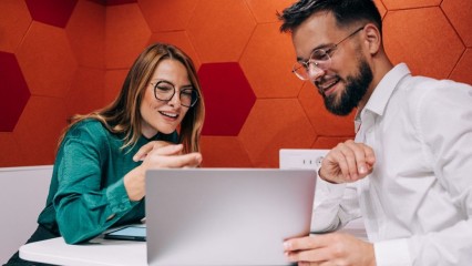 Deux personnes à table, en train de regarder un écran d'ordinateur