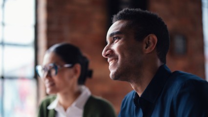 Homme souriant, avec une femme en arrière plan