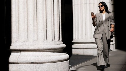 Femme d'affaires, téléphone en main, marchant entre des colonnes