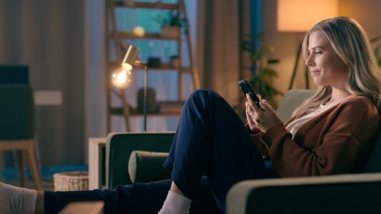 Femme dans un canapé regardant son écran de smartphone