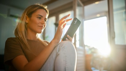 Femme assise avec son téléphone en main par une journée ensoleillée