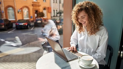 Femme en terrasse, avec un café, devant son PC
