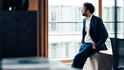 Homme appuyé contre une table, dans un immeuble de bureaux