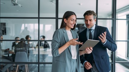 Un homme et une femme dans un bureau, avec une salle de réunion en arrière plan