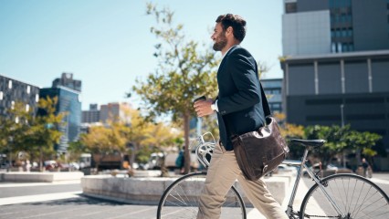 Homme à vélo au milieu d'immeubles modernes et d'une place végétalisée.