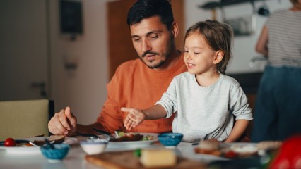 Un homme avec sa fille, à table, en train de manger