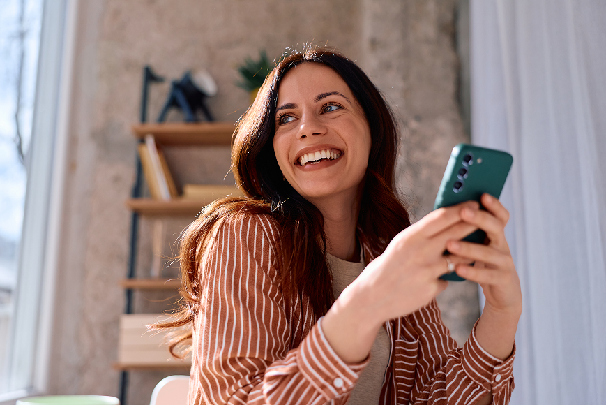 Femme riant joyeusement devant son téléphone