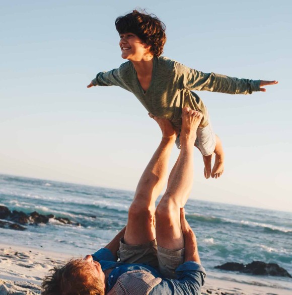 2 enfants sur la plage, dont un faisant semblant de s'envoler.