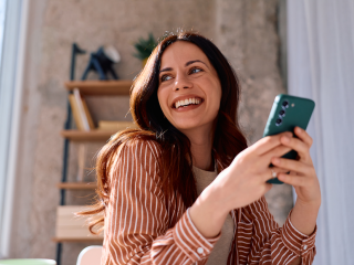 Femme riant joyeusement devant son téléphone